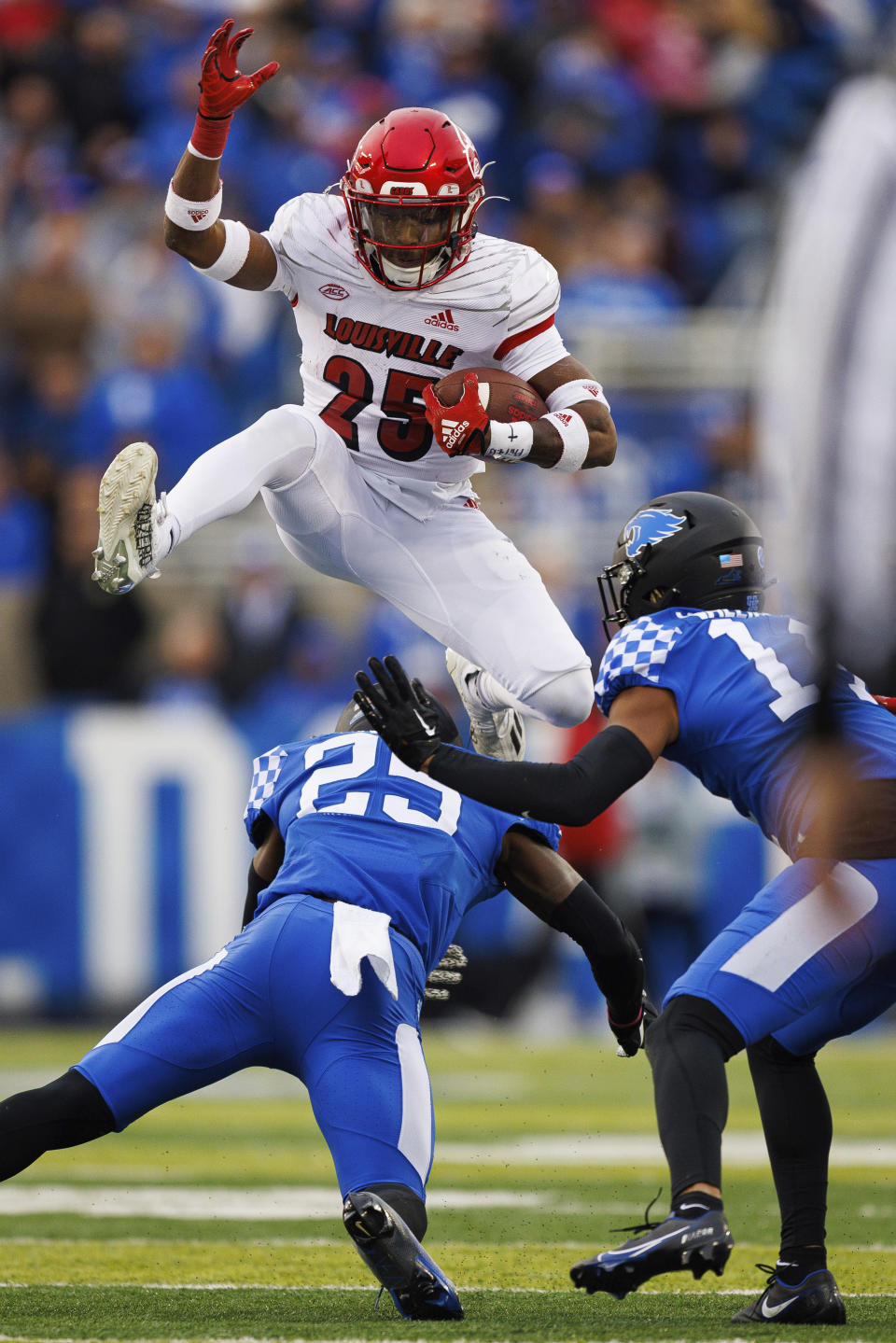 Louisville running back Jawhar Jordan (25) hurdles over Kentucky defensive back Jordan Lovett (25) during the first half of an NCAA college football game in Lexington, Ky., Saturday, Nov. 26, 2022. (AP Photo/Michael Clubb)