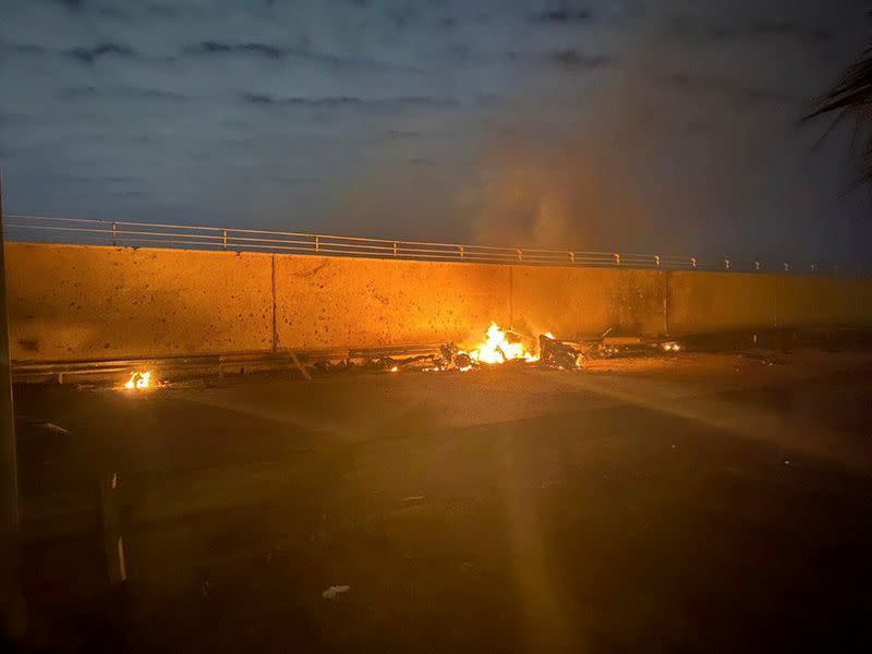 Burning debris are seen on a road near Baghdad International Airport