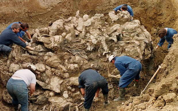 In September 1996, International War Crimes Tribunal investigators clearing away soil and debris from dozens of Srebrenica victims buried in a mass grave - Credit: AP Photo/Staton R. Winter