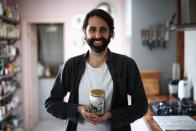 Ander Zabala poses inside his house with a jar containing all of the non-recyclable waste his household of two produced in one month, London