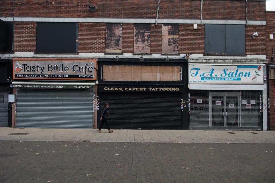 ROMFORD, ENGLAND - OCTOBER 27: A woman walks past rundown closed shops in North Street on October 27, 2022 in Romford, England. (Photo by John Keeble/Getty Images)