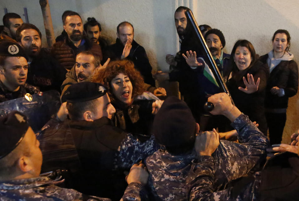 Anti-government protesters scuffle with riot police, as they demand the release of those taken into custody the night before, outside a police headquarter, in Beirut, Lebanon, Wednesday, Jan. 15, 2020. Lebanese security forces arrested 59 people, the police said Wednesday, following clashes overnight outside the central bank as angry protesters vented their fury against the country's ruling elite and the worsening financial crisis. (AP Photo/Hussein Malla)