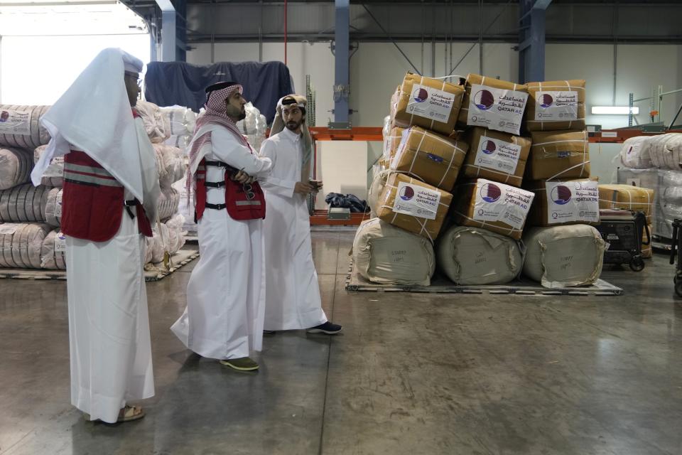 Qatari Red Crescent employees pass by supplies of assistance package to be sent for earthquake hit areas of Turkey, at Al-Udeid Air Base in Qatar, Tuesday, Feb. 7, 2023. (AP Photo/Kamran Jebreili)