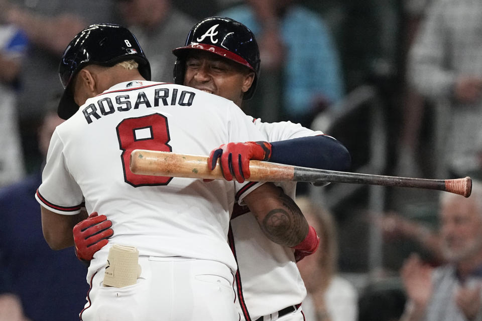 Atlanta Braves' Eddie Rosario (8) gets a hug from Ozzie Albies after hitting a solo home run against the Cincinnati Reds during the eighth inning of a baseball game Wednesday, April 12, 2023, in Atlanta. (AP Photo/John Bazemore)