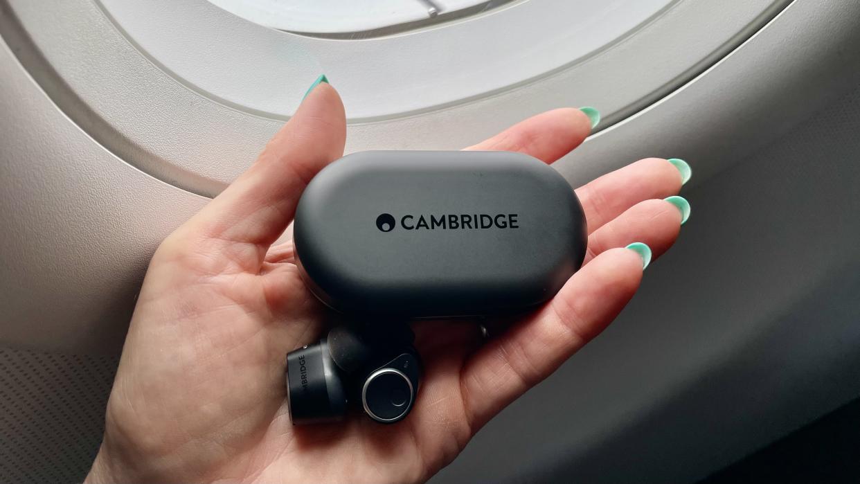  Cambridge Audio Melomania M100, held in a hand with blue fingernails, in the window of an aircraft. 