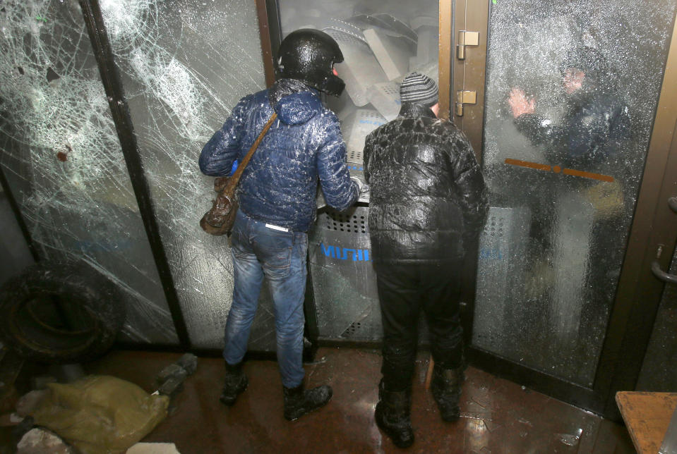 Protesters negotiate with police during an attack of the Ukrainian House building in central Kiev, Ukraine, early Sunday, Jan. 26, 2014. New violence erupted in Ukraine's capital during the night as a large crowd attacked the government exposition and conference hall where police were stationed inside. Early Sunday, demonstrators were throwing firebombs into the Ukrainian House building and setting off fireworks, and police responded with tear gas. (AP Photo/Sergei Grits)