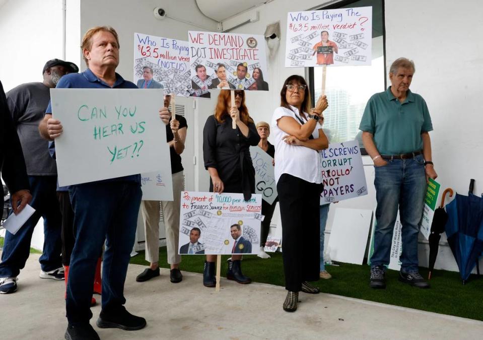 6 de junio de 2023; Miami, Florida. / Cecile Tavera-Webman, residente de Coconut Grove, lleva un cartel preguntando quién está pagando el veredicto judicial de $63,5 millones contra el comisionado de la ciudad de Miami, Joe Carollo, durante una protesta. Los manifestantes piden una investigación del Departamento de Justicia y la expulsión de Carollo en el Ayuntamiento de Miami.