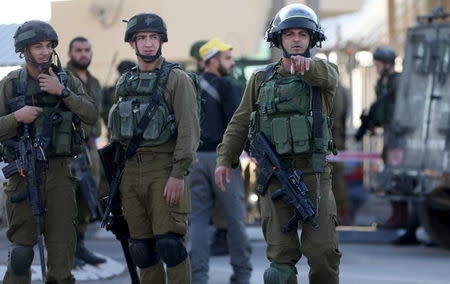 An Israeli soldier gestures as he stands guard with others at the scene of what an Israeli police spokeswoman said was a car-ramming attempt by a Palestinian at the West Bank checkpoint of Qalandia, near Ramallah, December 18, 2015. REUTERS/Mohamad Torokman