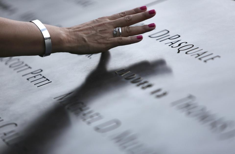 An attendee touches the stone at the 9/11 Memorial during ceremonies marking the 12th anniversary of the 9/11 attacks on the World Trade Center in New York