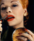 <p>You may not have thought of the comedienne as having a great interest in beauty, but she actually started her career as a model. Here she masterfully applies her lipstick to match her nails and dyed red hair. </p>