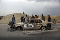 Afghans watch a civilian vehicle burnt after being shot by US forces following an attack near the Bagram Air Base, north of Kabul, Afghanistan, Tuesday, April 9, 2019. Three American service members and a U.S. contractor were killed when their convoy hit a roadside bomb on Monday near the main U.S. base in Afghanistan, the U.S. forces said. The Taliban claimed responsibility for the attack. (AP Photo/Rahmat Gul)