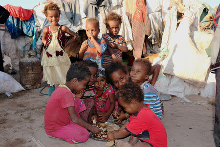 Children eat bread at a camp sheltering displaced people from the Red Sea port city of Hodeidah near Aden, Yemen November 12, 2018. Pictures taken November 12, 2018. REUTERS/Fawaz Salman