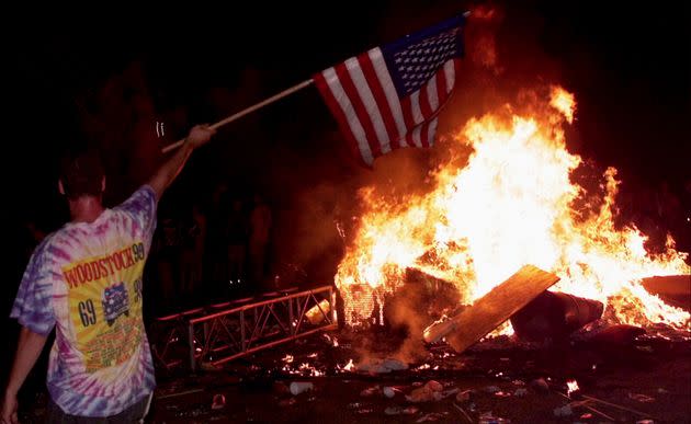 A young man waves the American flag in the midst of wreckage at Woodstock '99. (Photo: Netflix)