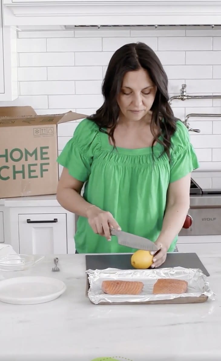 A woman preparing a salmon dish from her Home Chef meal delivery kit