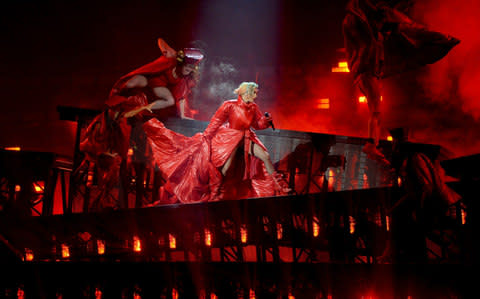 Lady Gaga in a red devil-esque costume on a tilting stage  - Credit: Jason Merritt/Getty Images for Live Nation