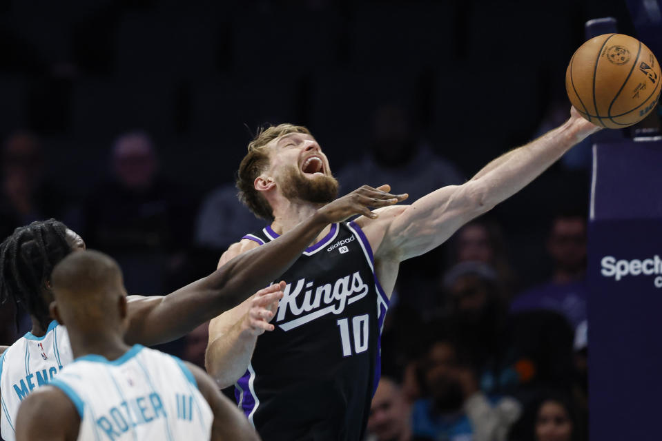 Sacramento Kings forward Domantas Sabonis (10), drives to the basket against Charlotte Hornets center Nathan Mensah as guard Terry Rozier looks on during the first half of an NBA basketball game in Charlotte, N.C., Wednesday, Jan. 10, 2024. (AP Photo/Nell Redmond)