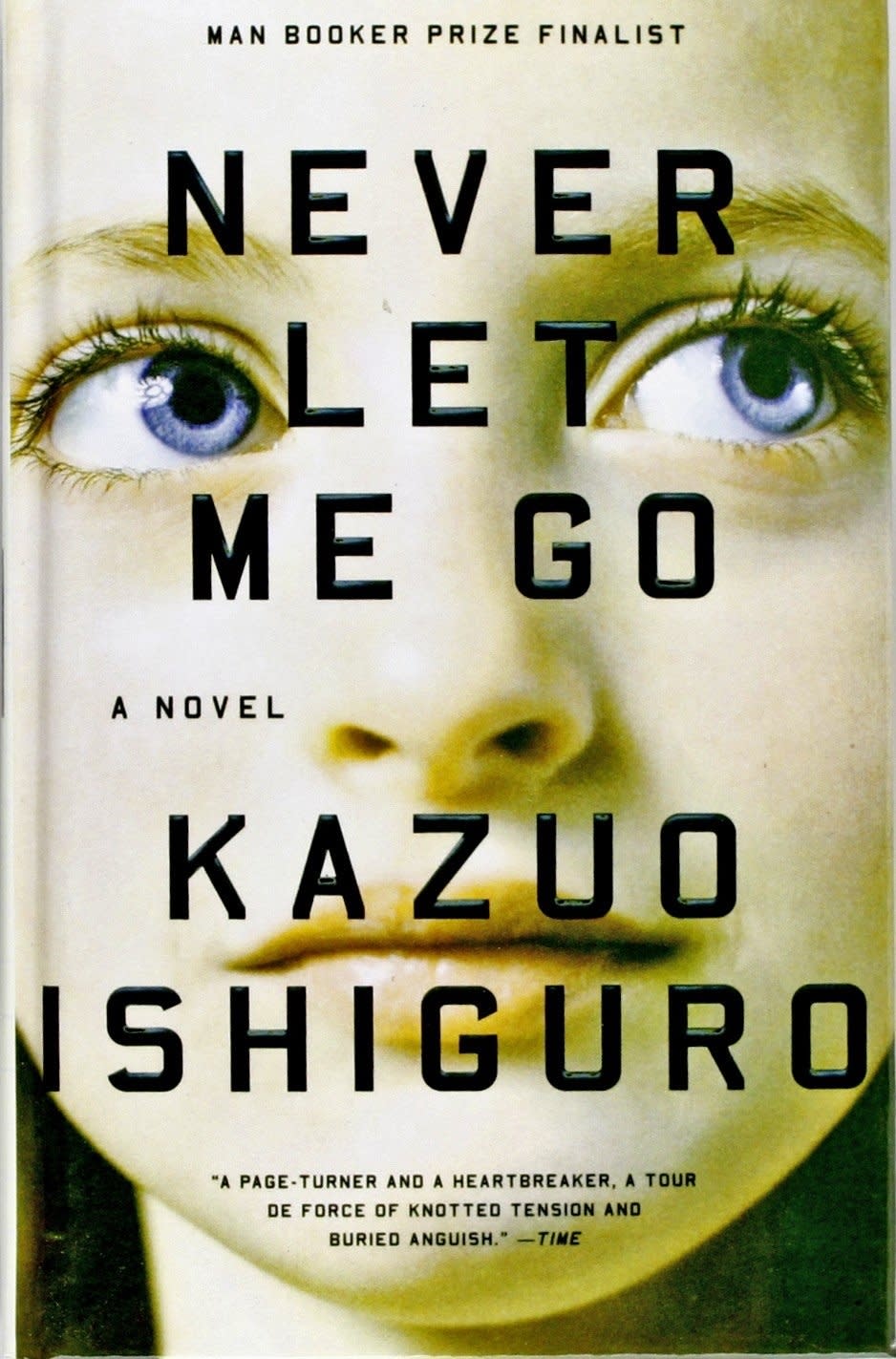Close-up of 'Never Let Me Go' book cover by Kazuo Ishiguro, featuring title and author's name with a pair of eyes