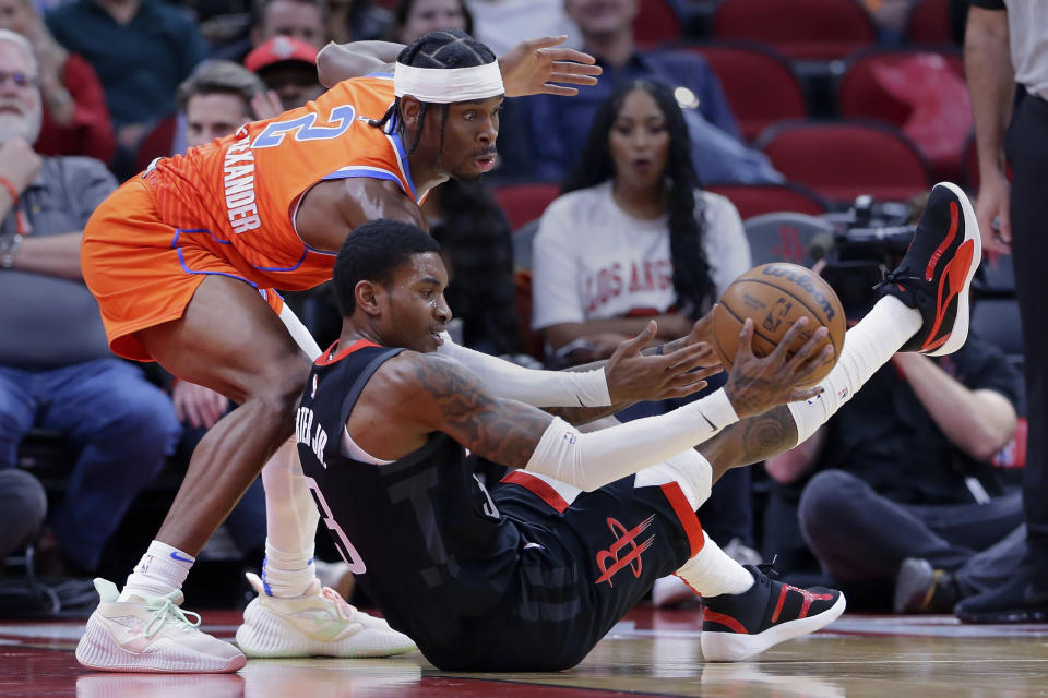 Oklahoma City Thunder guard Shai Gilgeous-Alexander (2) reaches for the ball as Houston Rockets guard Kevin Porter Jr. (3) falls backward during the first half of an NBA basketball game Saturday, Nov. 26, 2022, in Houston. (AP Photo/Michael Wyke)