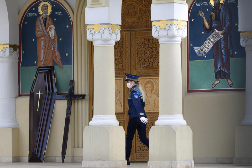 In this Sunday, April 12, 2020, photo a police officer walks while monitoring a church to prevent worshipers from attending the religious service during the coronavirus pandemic on Palm Sunday in Bucharest, Romania. For Orthodox Christians, this is normally a time of reflection, communal mourning and joyful release, of centuries-old ceremonies steeped in symbolism and tradition. But this year, Easter - by far the most significant religious holiday for the world's roughly 300 million Orthodox - has essentially been cancelled. (AP Photo/Andreea Alexandru)