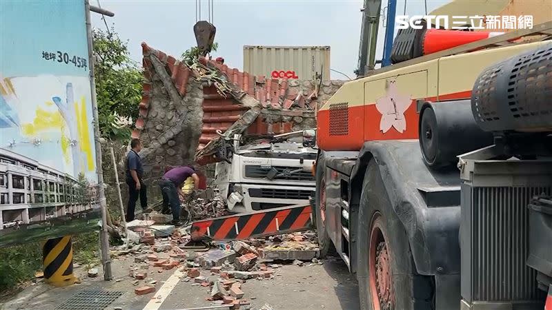 南投市貨櫃車撞倒寺廟牌樓，重壓車頭，駕駛和副駕駛受困。（圖／翻攝畫面）