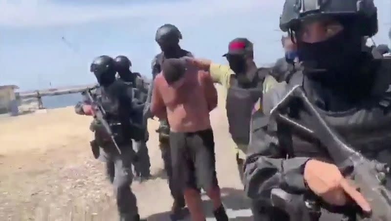 Venezuelan soldiers in balaclavas move a suspect from a helicopter after what Venezuelan authorities described was a "mercenary incursion", at an unknown location in this still frame obtained from Venezuelan government TV video