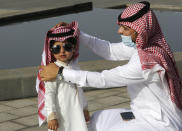 A Saudi man arranges his son's traditional "Ghutra", or head cover, after performing Eid al-Fitr prayer marking the end of the holy fasting month of Ramadan in Jiddah, Saudi Arabia, Thursday, May 13, 2021. (AP Photo/Amr Nabil)