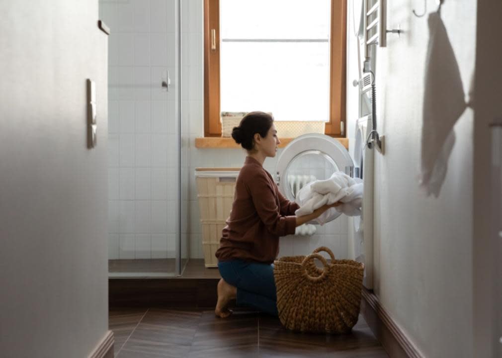 A woman putting laundry into a washing machine.