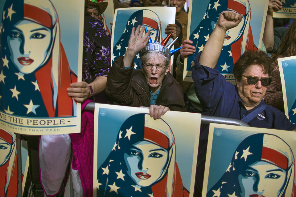 FILE - In this Sunday, Feb. 19, 2017 file photo, people carry posters during a rally against President Donald Trump's executive order banning travel from several Muslim-majority nations, in New York's Times Square. (AP Photo/Andres Kudacki)