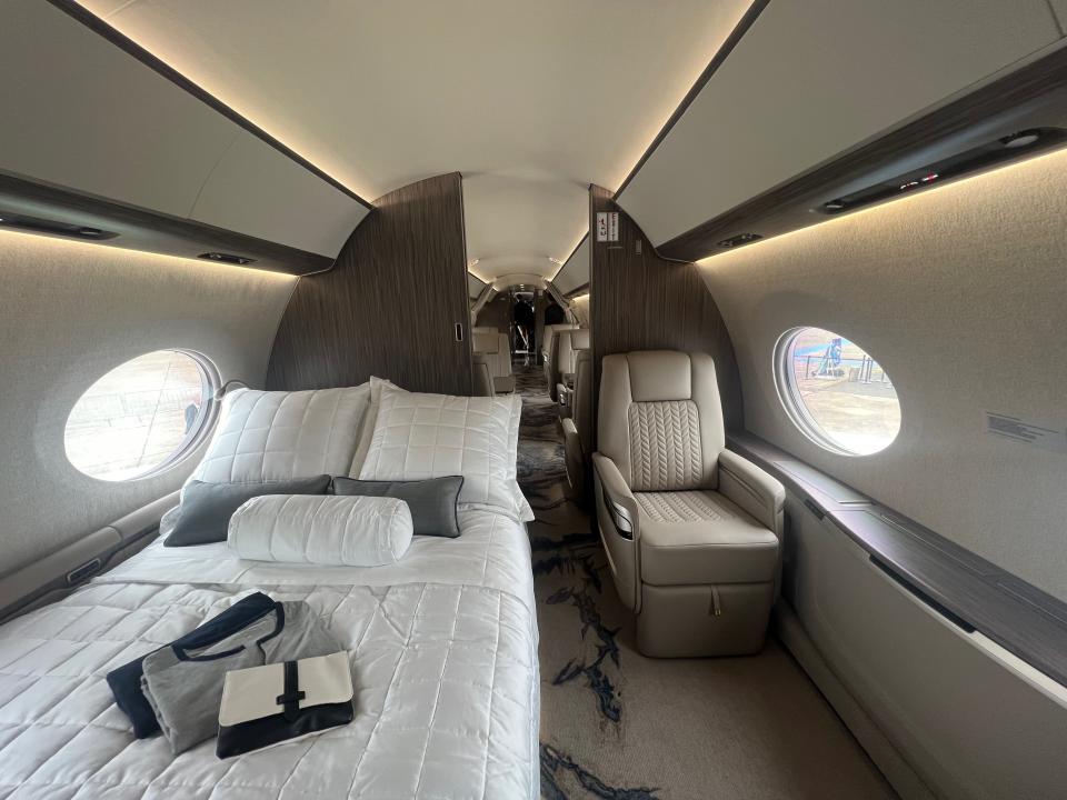 The bedroom with pajamas on the bed and a beige lounger.