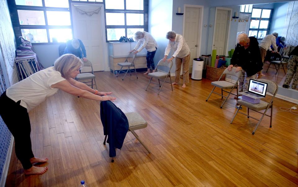 Bella Buddha Yoga owner Brenda Yarnold (left) leads a chair yoga class for seniors at the Belmar studio Monday, April 10, 2023.