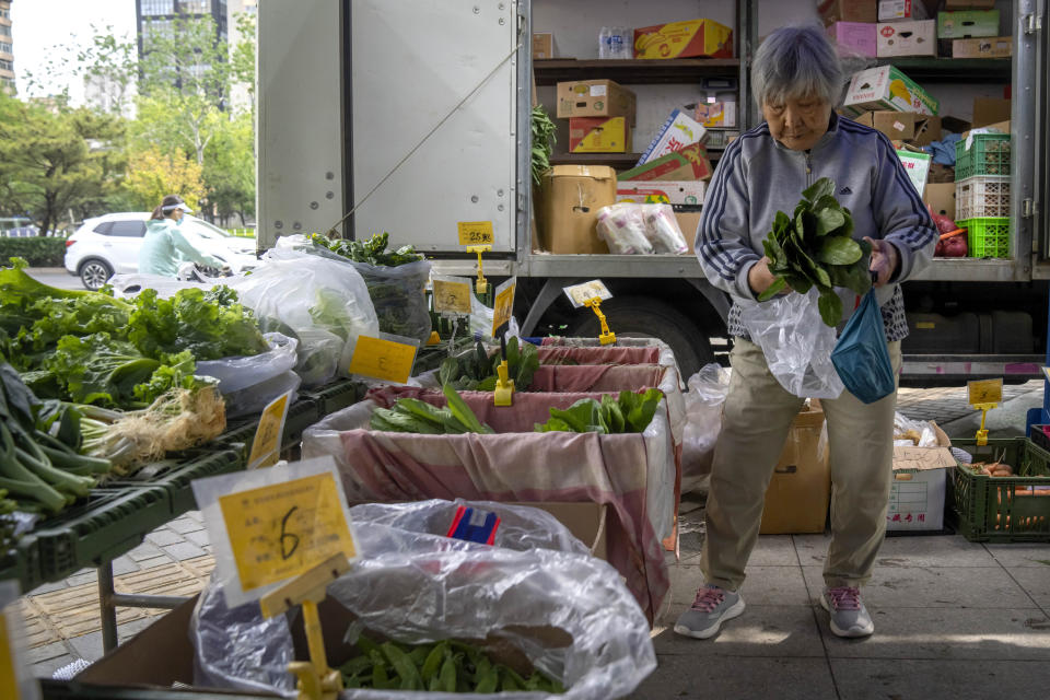 A woman shops for fresh vegetables at a pop-up market in Beijing, Thursday, April 28, 2022. Beijing shifted more classes online Thursday in a further tightening of COVID-19 restrictions, as China's capital seeks to prevent a wider outbreak. (AP Photo/Mark Schiefelbein)