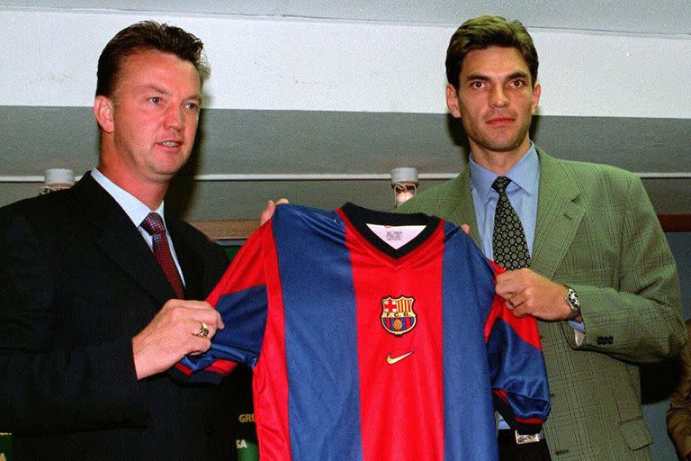 El futbolista argentino Mauricio Pellegrino, derecha, anteriormente del club argentino Vélez Sarsfield, levanta su nueva camiseta del club de Barcelona con el entrenador del Barcelona Louis Van Gaal después de firmar para el club catalán el viernes 28 de agosto de 1998