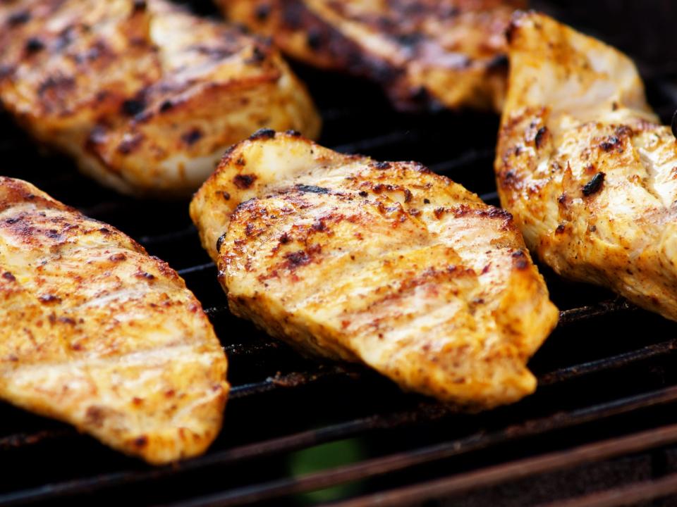 Five golden-brown chicken breasts on grill