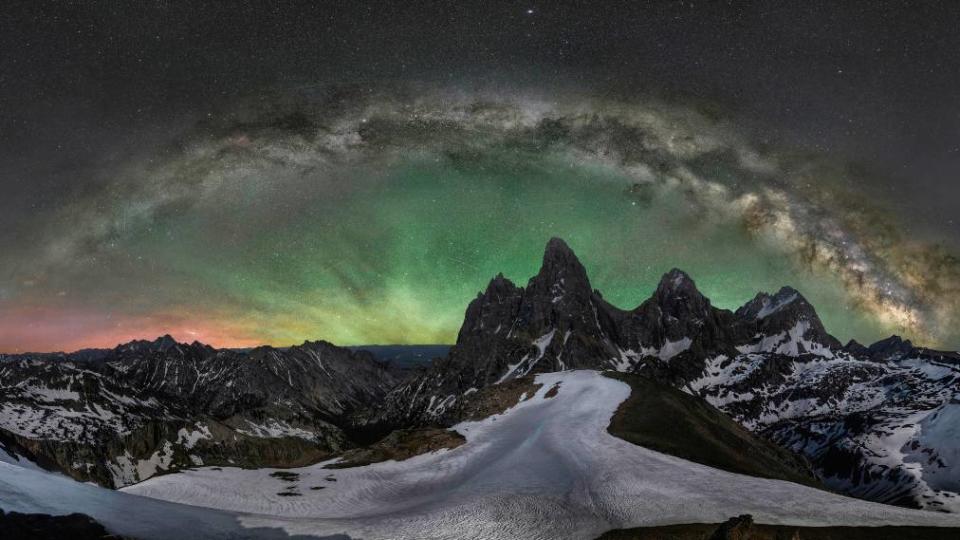 A panorama of the Grand Teton under a halo of green light.