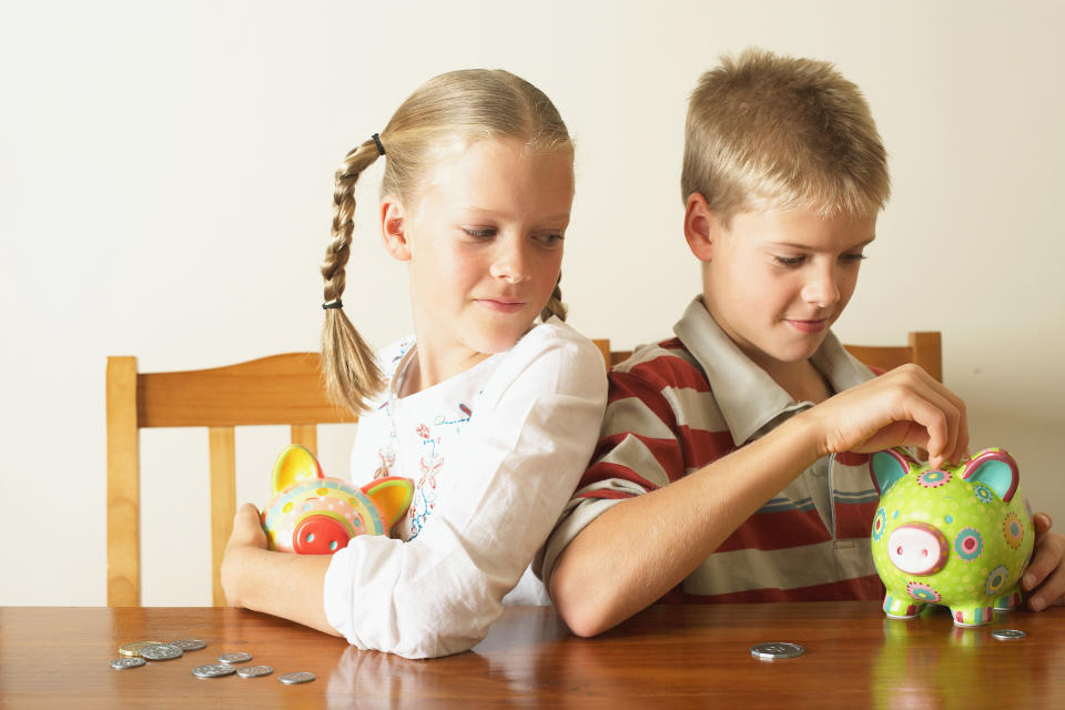 Pictured: Two blonde children with piggy banks. Image: Getty