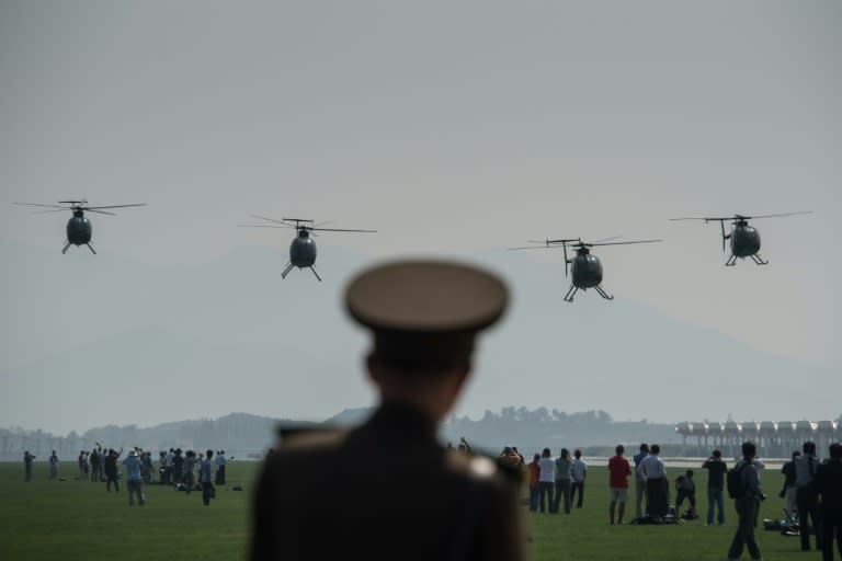 A North Korean soldier watches as Hughes MD-500 helicopters perform a fly-by during the first Wonsan Friendship Air Festival