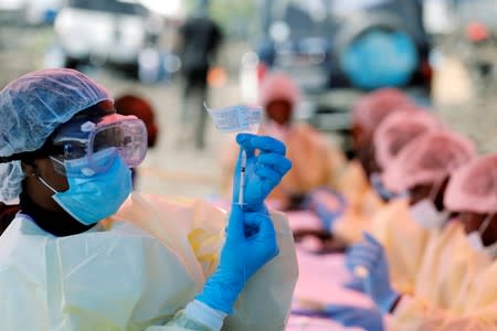 A health worker fills a syringe with Ebola vaccine before injecting it to a patient, in Goma