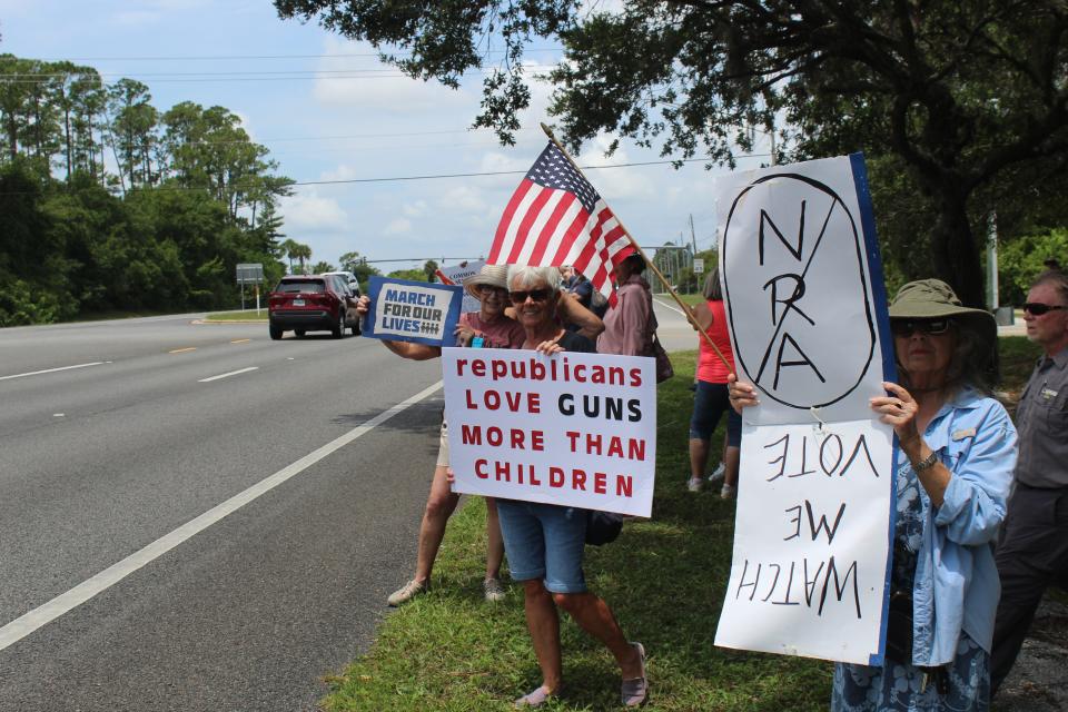Demonstrators hold up signs on Saturday along State Road 100 at Wadsworth Park during the March for Our Lives rally in Flagler Beach.