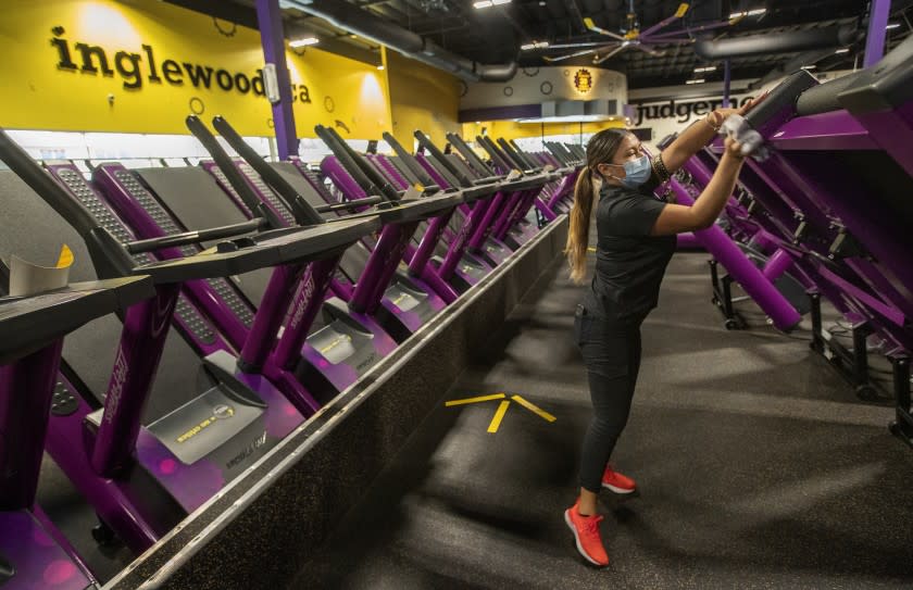 INGLEWOOD, CA - MARCH 15: Crystal Garcia, an assistant manager at Planet Fitness on Imperial Highway in Inglewood, wipes down treadmills with disinfectant while helping to prepare the fitness center for their re-opening tomorrow morning at 5am after being closed since July of 2020. Every other treadmill has a sign saying not available for use to ensure social distancing. The new guidelines allow for a maximum of 10 percent of capacity. (Mel Melcon / Los Angeles Times)
