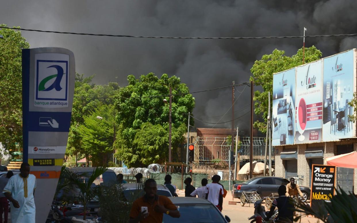 People watch as black smoke rises as the capital of Burkina Faso came under multiple attacks - AFP