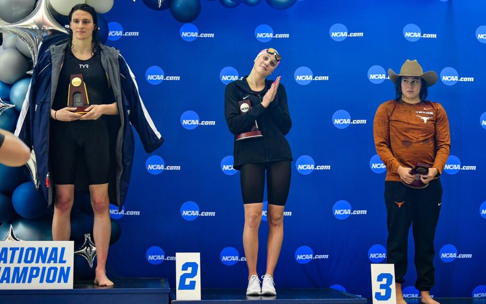 Lia Thomas accepts the winning trophy for the 500 Freestyle finals as second place finisher Emma Weyant and third place finisher Erica Sullivan watch during the NCAA Swimming and Diving Championships