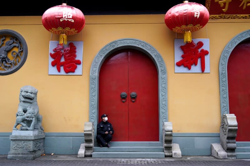 A security guard sits at the entrance of a closed temple in Shanghai