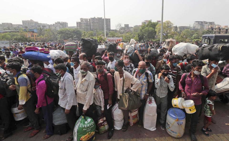 People wearing masks as a precaution against the coronavirus stand in queues to board trains at Lokmanya Tilak Terminus in Mumbai, India, Wednesday, April 14, 2021. India is experiencing its worst pandemic surge, with average daily infections exceeding 143,000 over the past week. (AP Photo/Rafiq Maqbool)