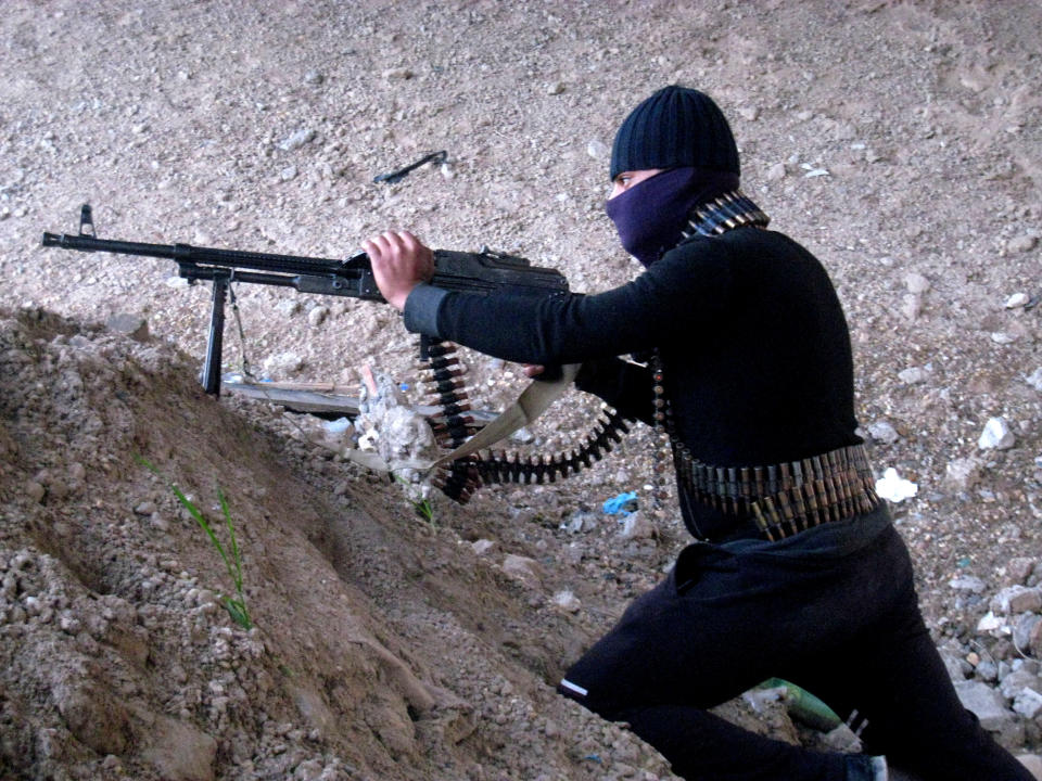 A gunmen takes cover during clashes with Iraqi security forces outside Fallujah, 40 miles (65 kilometers) west of Baghdad, Iraq, Sunday, Jan. 19, 2014. Violence across Iraq, including a series of car bombings and fighting between militants and government troops over control of the country's contested Anbar province, killed dozens Saturday, officials said. (AP Photo)