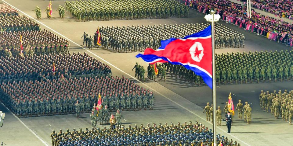 The flag of the DPRK flies amid a military parade in Pyongyang with hundreds of soldiers marching, April 25, 2022. Image provided by state media.