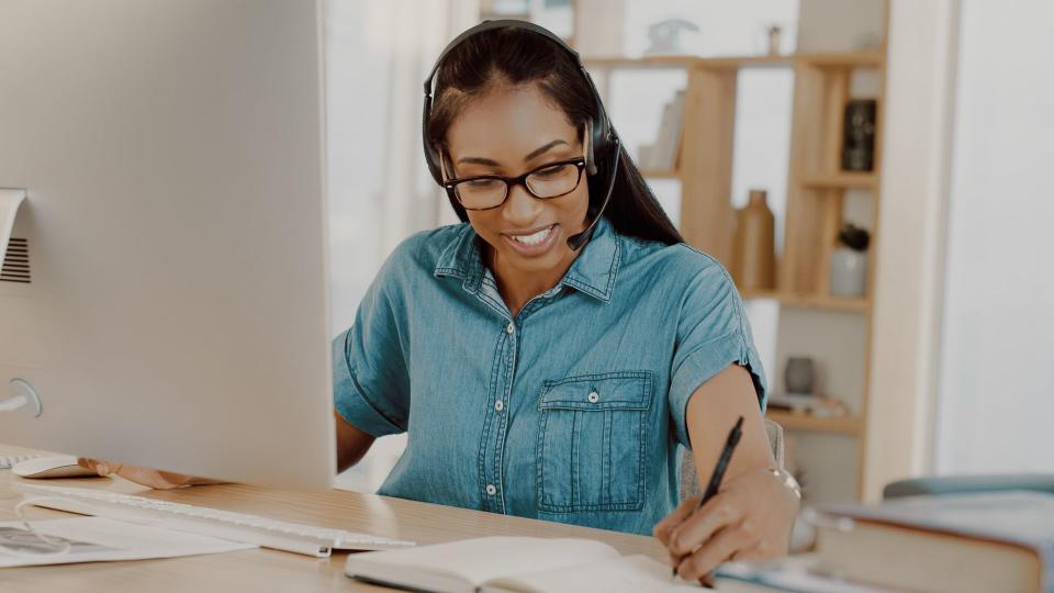 Shot of an attractive young businesswoman wearing headsets and working on a computer at home.