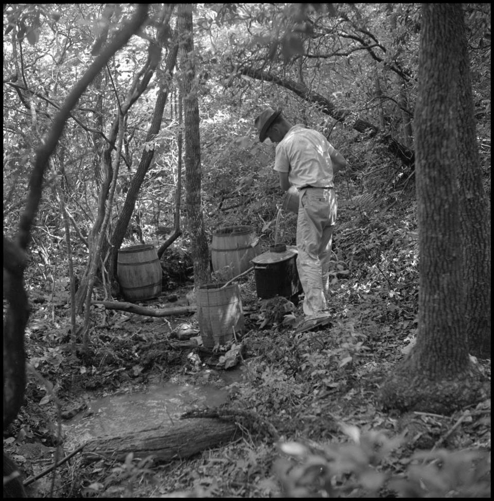 A man setting up a moonshine distillery in the forest. Illegal moonshiners and bootleggers, who continued to profit on a small scale from the Texas Prohibition, were among the opponents of liquor by the drink. "It was commonly believed that the Texas beer industry, quite robust at the time with both Lone Star and Pearl going strong, was also covertly in opposition," says architect John Waston, who worked on San Antonio's HemisFair '68..