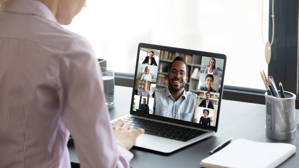 Close up of woman worker sit at desk talk speak on video call with multiracial colleagues or friends, female employee have online briefing with international team, engaged webcam conference at home