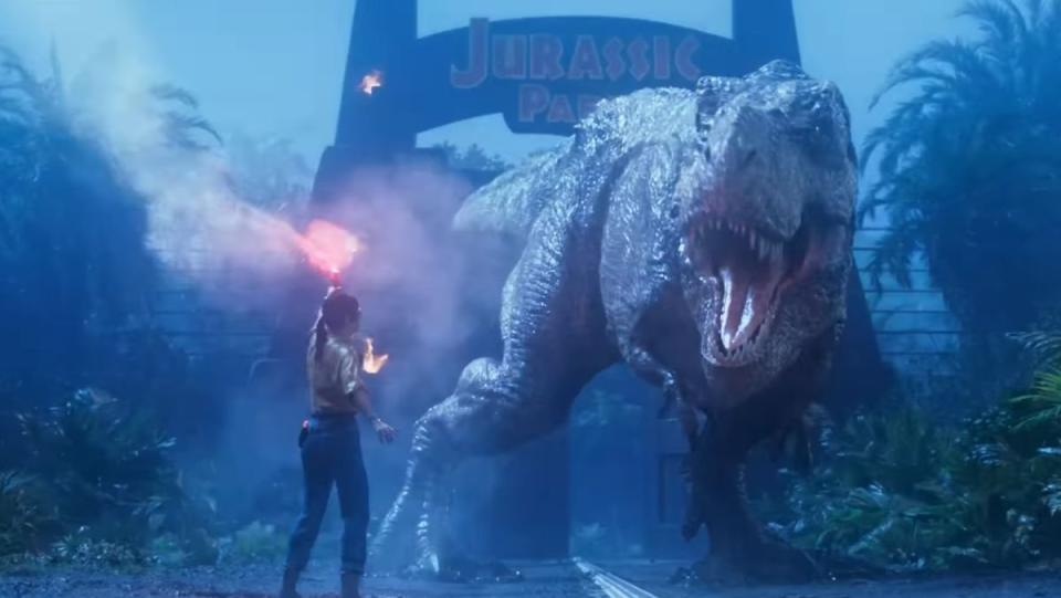 image from jurassic park survival trailer of a woman with a torch standing in front of a t-rex