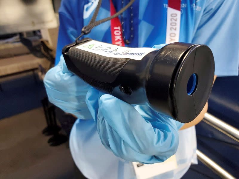 A Tokyo 2020 Olympics volunteer holds a device that generates a piercing noise to warn spectators of balls headed for the stands at Yokohama Baseball Stadium, Yokohama